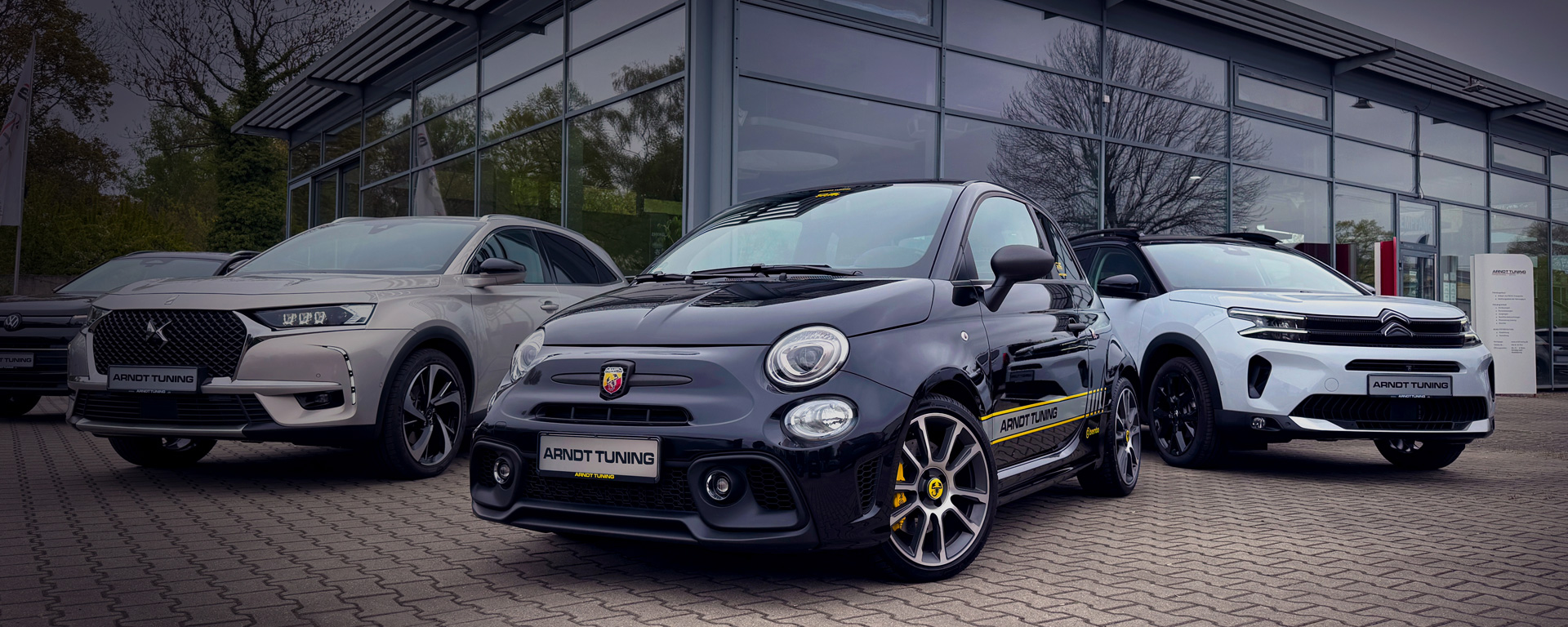 Fahrzeugangebot Arndt Tuning Berlin – Abarth 500, DS 7 Crossback und Citroën C5 Aircross vor Firmengebäude mit Glasfassade.