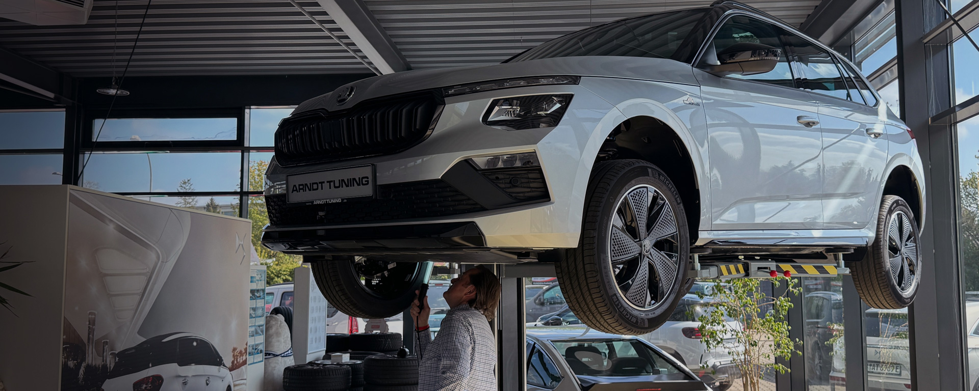 Fahrzeug auf einer Hebebühne bei Arndt Tuning Berlin – Mitarbeiter prüft Unterboden im Showroom für transparenten Ankauf.