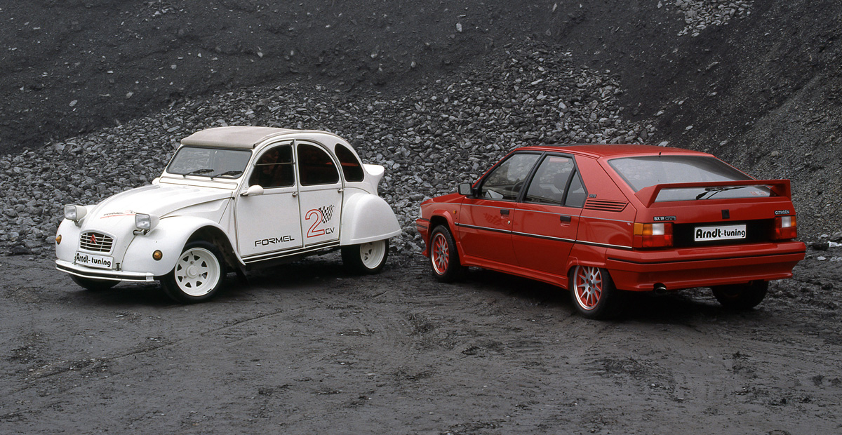 Citroën 2CV mit Breitreifen und BX Umbau von Arndt Tuning Berlin – klassische Fahrzeuge auf Schotterfläche als Symbol für Tuning-Tradition