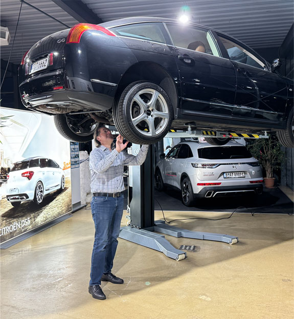 Fahrzeug auf einer Hebebühne mit einer Person bei der Fahrzeugbewertung im Showroom