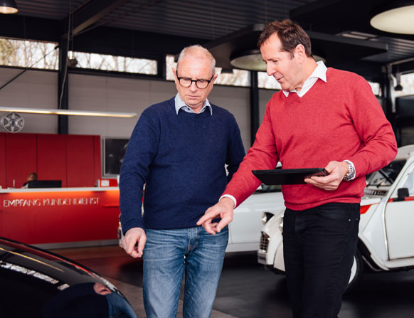 Autoankauf und Beratung – Mitarbeiter erklärt Kunden Fahrzeugdetails im Showroom