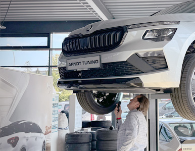 Zwei Personen im Arndt Tuning Berlin Showroom bei einer Fahrzeugbewertung, umgeben von Autos